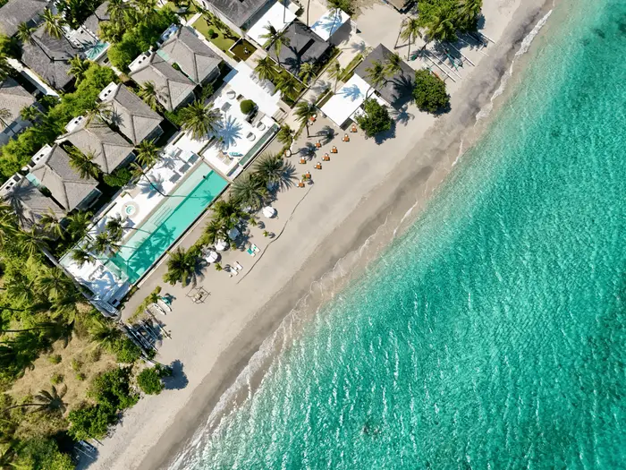 Aerial drone view of a luxury beachfront resort with private pool and tropical beach in Bali managed by Bali Assist Co