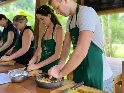 Tourists learning to grind spices during an authentic Balinese cooking class in Ubud organized by Bali Assist Co