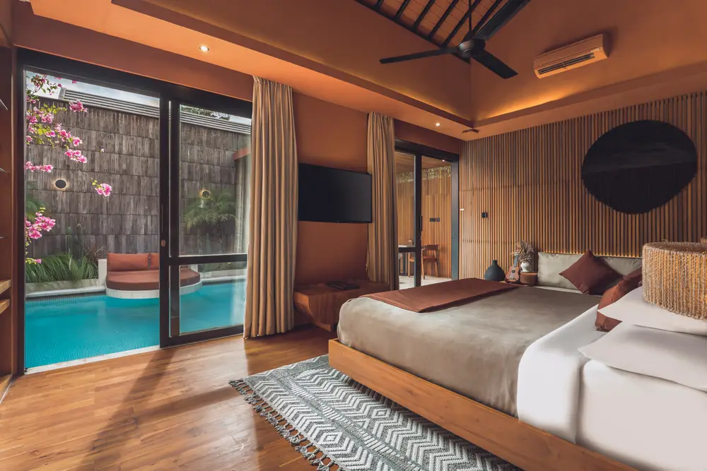 Cozy luxury boutique villa bedroom with earth tone interior and pool view in Bali by Bali Assist Co