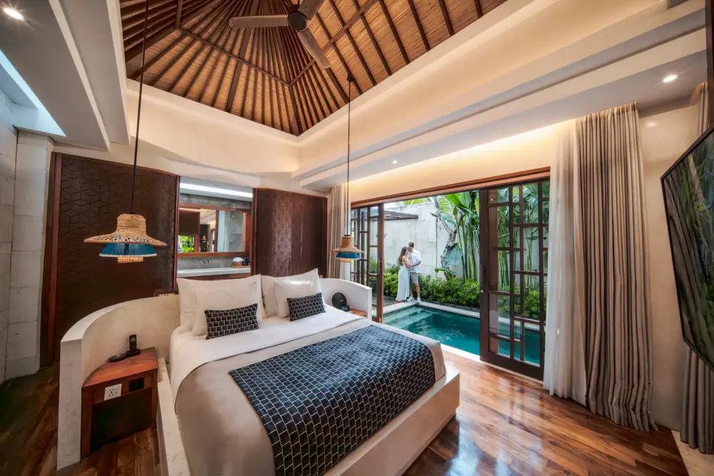 Couple standing by a private plunge pool viewed from a luxury villa bedroom in Bali curated by Bali Assist Co