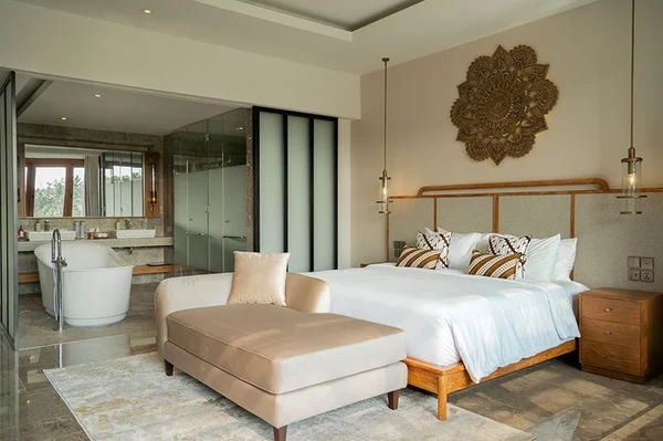 Modern luxury boutique resort suite with elegant king bed and lounge sofa in Bali curated by Bali Assist Co
