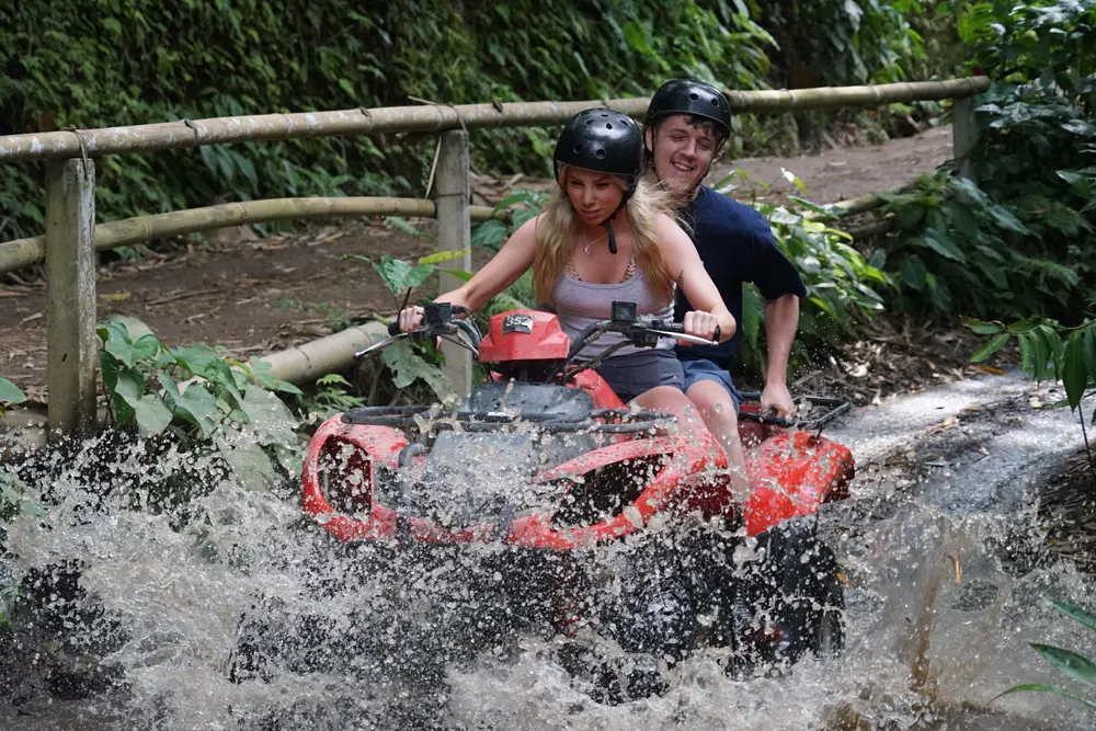 Woman riding ATV quad bike splashing through river water trail in Ubud for The Discovery Day 3 by Bali Assist Co