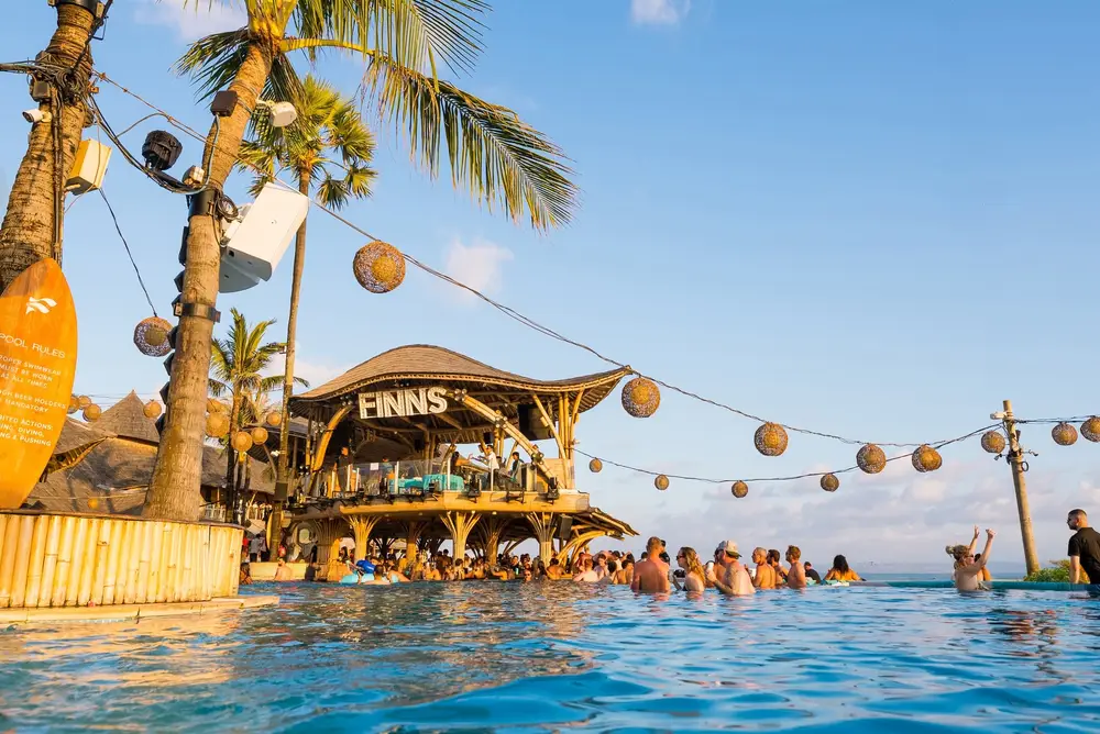 Guests relaxing at infinity pool with bamboo structure at Finns Beach Club Canggu for The Grand Escape Day 3 by Bali Assist Co