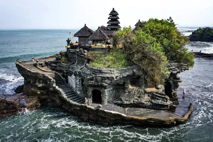 Iconic Tanah Lot sea temple perched on a rock cliff surrounded by ocean waves for The Grand Escape Day 4 by Bali Assist Co