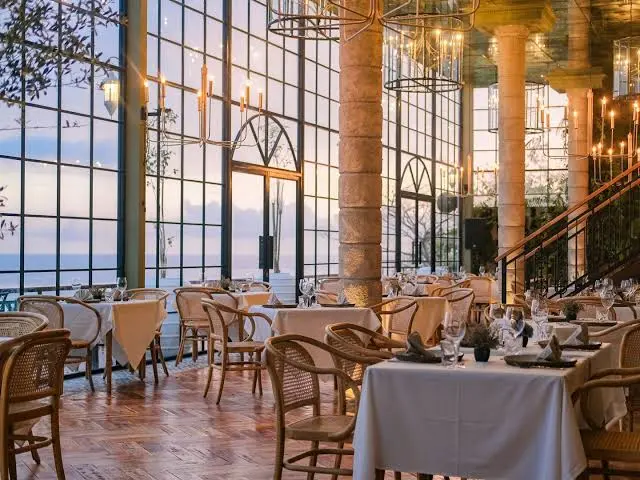 Elegant indoor dining area with large glass windows at The Cliff at Canna for The Grand Escape by Bali Assist Co