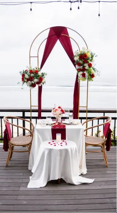 Private romantic dinner table setup with flower arch overlooking ocean at The Cliff at Canna by Bali Assist Co