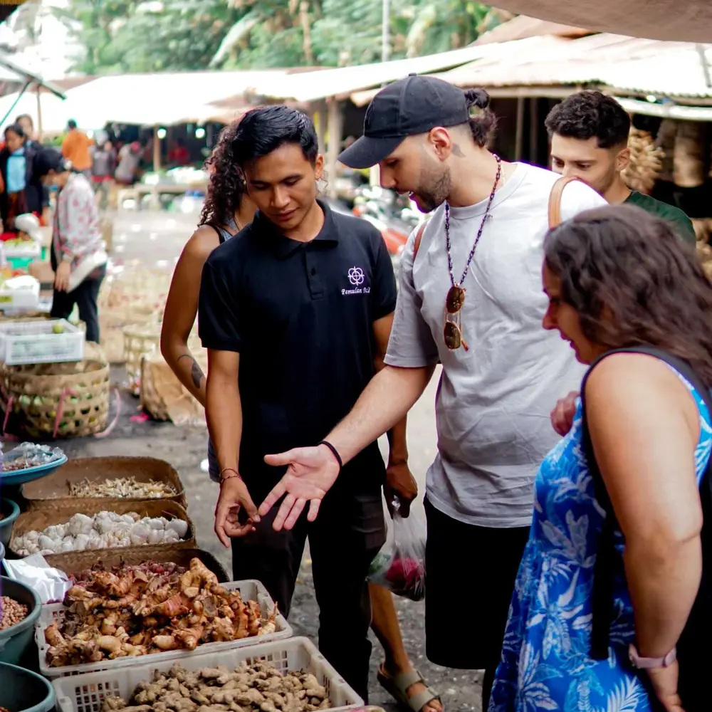 Local guide explaining fresh ingredients to tourist at local market in Ubud for The Grand Escape by Bali Assist Co