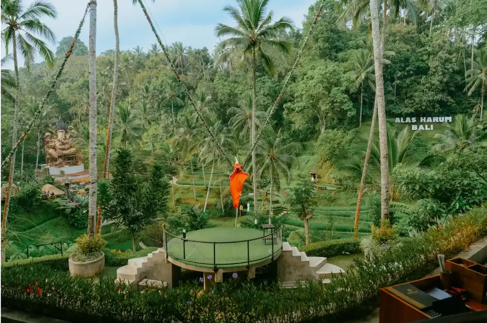 Woman in orange dress riding the iconic Bali Swing at Alas Harum Ubud for The Indulgence Day 4 by Bali Assist Co