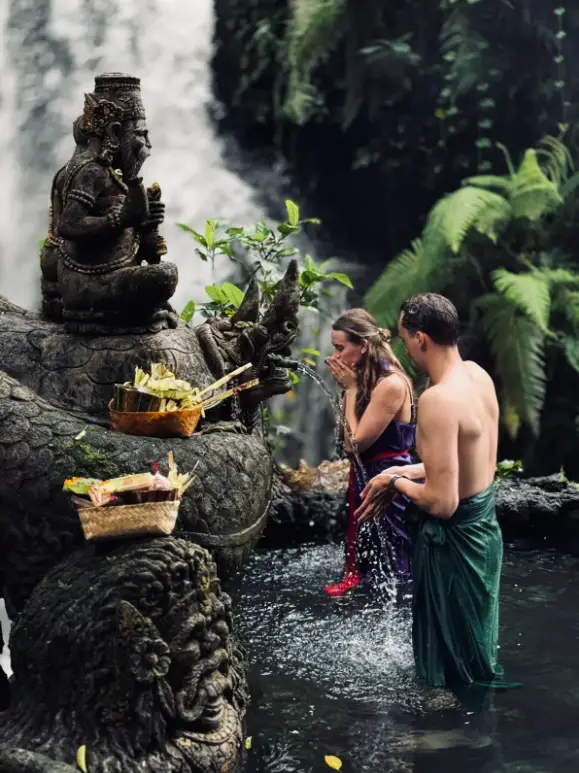 Couple receiving holy water blessing at Taman Beji Waterfall for The Indulgence Day 7 by Bali Assist Co