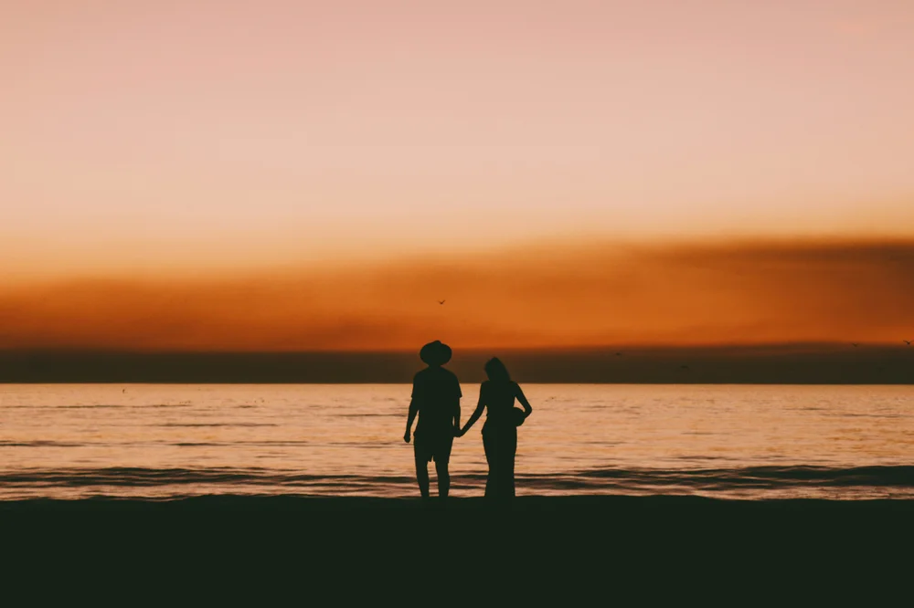 Couple taking a romantic beach walk during sunset in Bali for The Signature Journey honeymoon package by Bali Assist Co