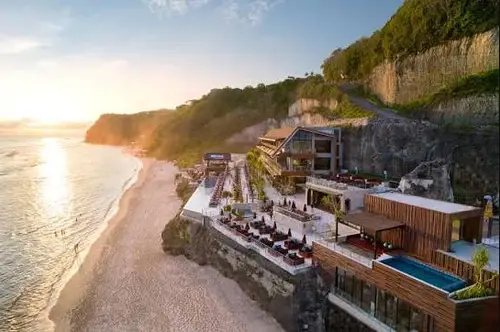 Luxury cliffside beach club at Melasti Beach with infinity pool overlooking ocean during golden hour sunset by Bali Assist Co