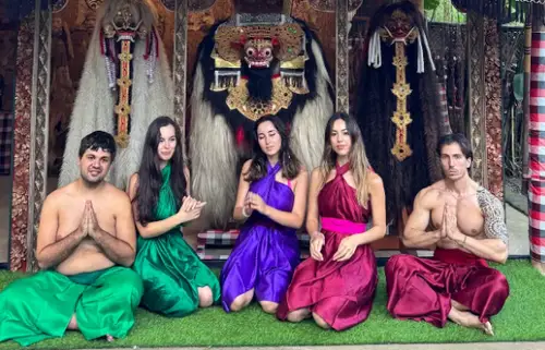 Women in colourful sarongs posing in front of Taman Beji Waterfall entrance gate by Bali Assist Co
