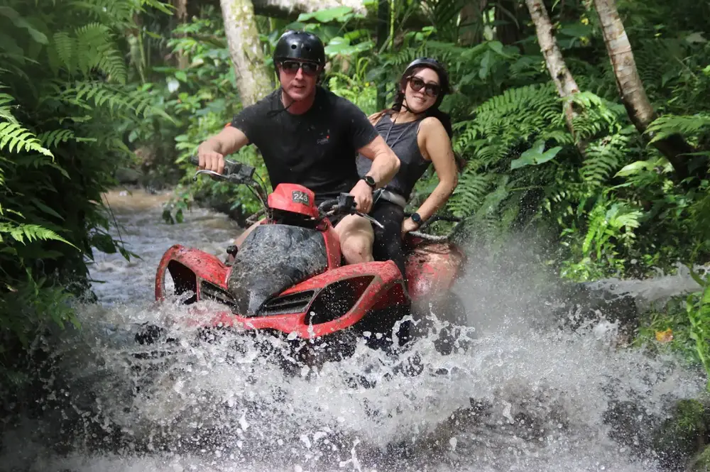 Tourists riding ATV quad bike through muddy water trail in Ubud jungle for The Signature Journey Day 6 by Bali Assist Co