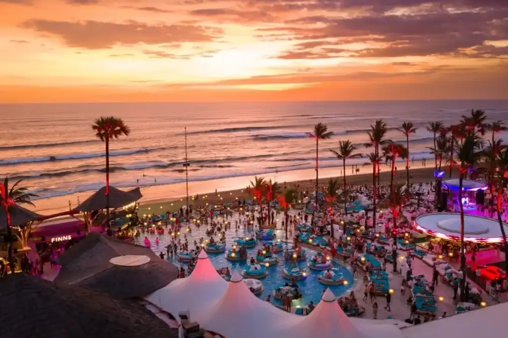 Golden sunset reflection over pool and ocean at Finns Beach Club Canggu by Bali Assist Co
