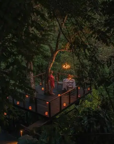 Couple enjoying candlelit romantic dinner on private tree deck surrounded by jungle at Kamandalu Ubud for The Ultimate Bali Journey Day 5 by Bali Assist Co