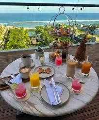 Afternoon tea setup with tropical juice on marble table overlooking resort ocean pool at The Apurva Kempinski Bali by Bali Assist Co