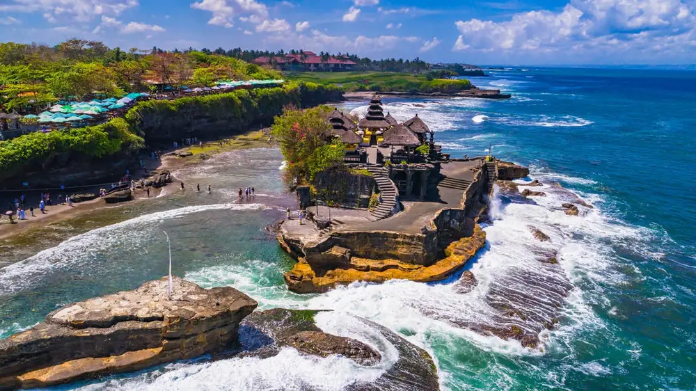 Crashing waves surrounding Tanah Lot temple rock in Tabanan Bali by Bali Assist Co